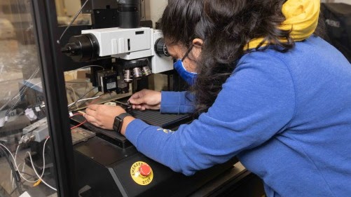 Student conducting materials testing under a microscope